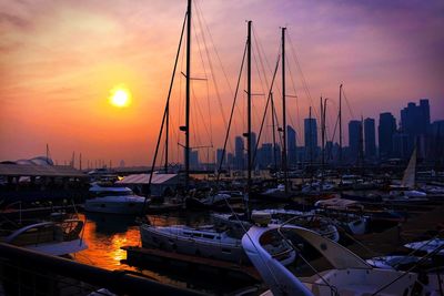 Boats moored at harbor against sky during sunset