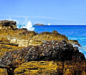 Scenic view of sea by cliff against blue sky