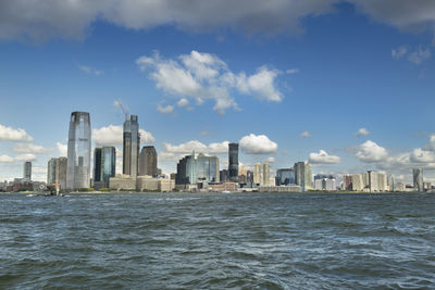 Sea by modern buildings against sky in city