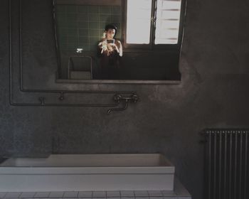 Reflection of man taking selfie in mirror at bathroom
