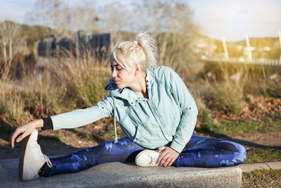 Woman stretching on field against sky