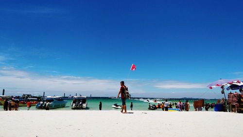 People on beach against blue sky