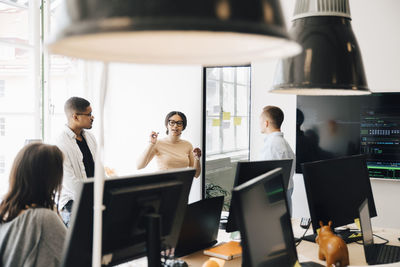 Computer programmers discussing while standing in creative office