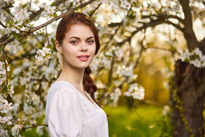 Portrait of young woman standing against plants