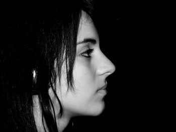 Profile view of young woman against black background