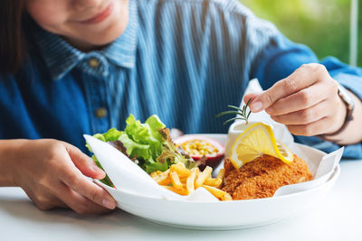 Closeup image of a female chef cooking and decorating a dish of fish and chips