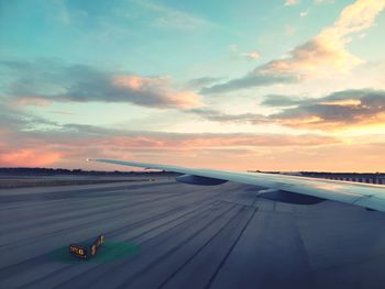 Airplane on runway against sky during sunset