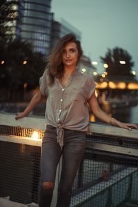 Portrait of smiling young woman in city at night