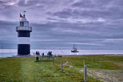 Lighthouse by sea against sky