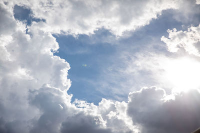 Low angle view of sunlight streaming through clouds