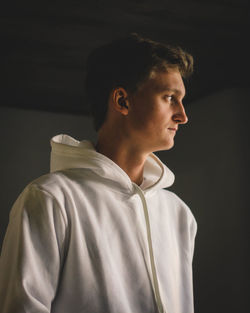 Portrait of young man looking away against black background