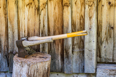 Two wooden axes stuck in the wood chopping trunk. in the background, a wooden wall of the old house.