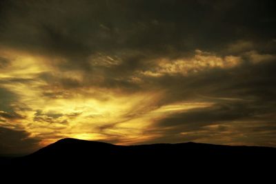 Silhouette of landscape against cloudy sky