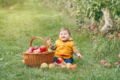 Baby boy holding fruits in basket at park