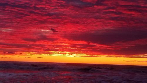 Scenic view of sea against dramatic sky during sunset