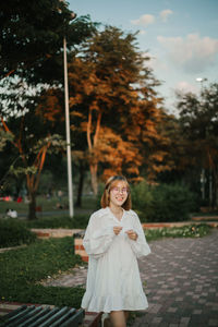 Portrait of young woman standing against trees