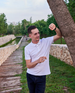 Rear view of young man standing on footbridge against sky