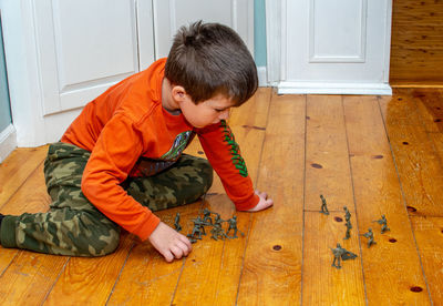 Young boy plays with toy soldiers on the floor