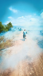 Rear view of man riding motorcycle against sky