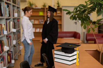 Rear view of woman wearing graduation gown standing at home