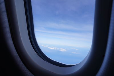 Close-up of airplane window against sky