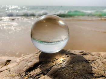 Close-up of crystal ball on beach against sky