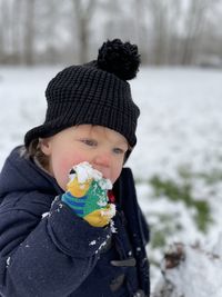 Cute boy eating food outdoors during winter