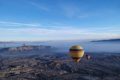 Hot air balloons flying over cappadocia against blue sky