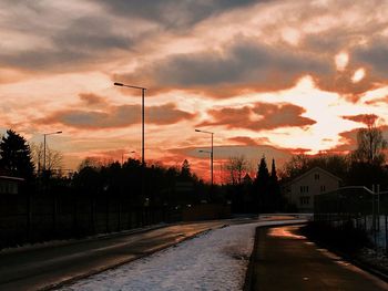 Road in city against sky at sunset