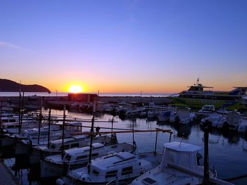 Boats moored at harbor during sunset