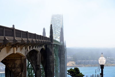 Arch bridge over river and buildings against clear sky