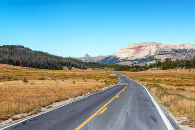 Road by mountains against clear blue sky