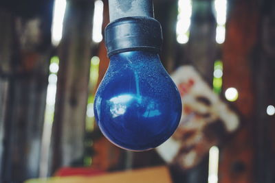 Close-up of blue light bulb hanging in room