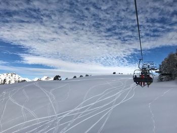 Ski lift over snowcapped mountains against sky