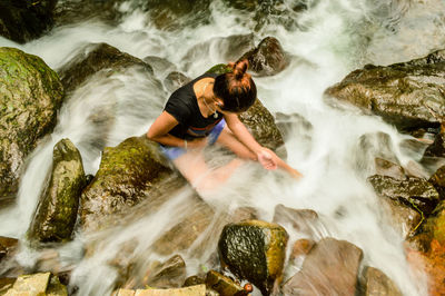 High angle view of woman sitting on rock in river