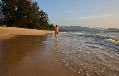 Full length of man standing on beach against sky