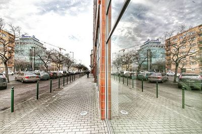 Road passing through city against cloudy sky