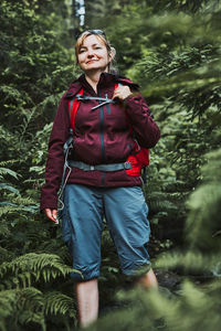 Woman with backpack hiking in forest, actively spending summer vacation close to nature