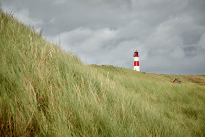 Lighthouse on field against sky