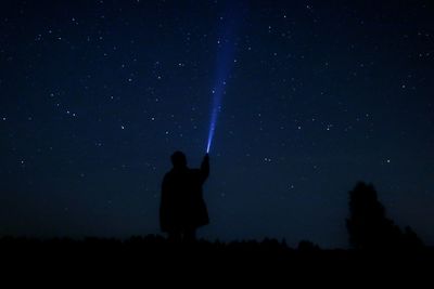 Silhouette man standing on field against sky at night