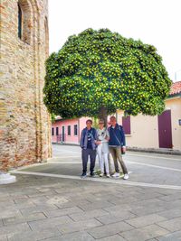 People standing on footpath by tree