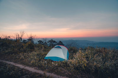 Tent on field against sky at sunset