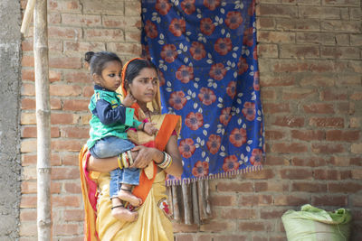 Full length of mother and daughter against wall