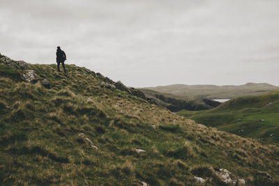 Rear view of man walking on mountain against sky