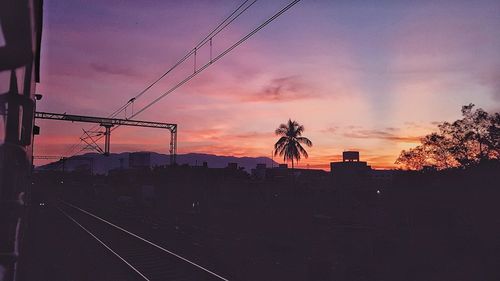 Silhouette railroad tracks against sky during sunset