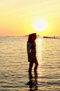 Silhouette woman standing in sea during sunset