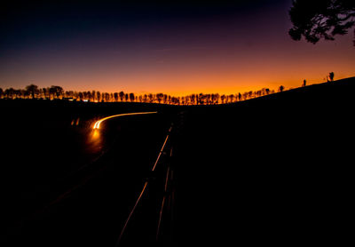 Silhouette bridge over road against sky during sunset
