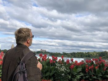 Man standing by flowering plants against sky