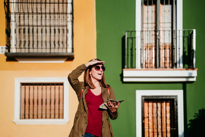 Woman wearing hat standing against building