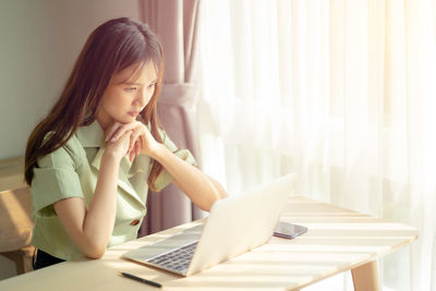 Midsection of woman using mobile phone while sitting on table